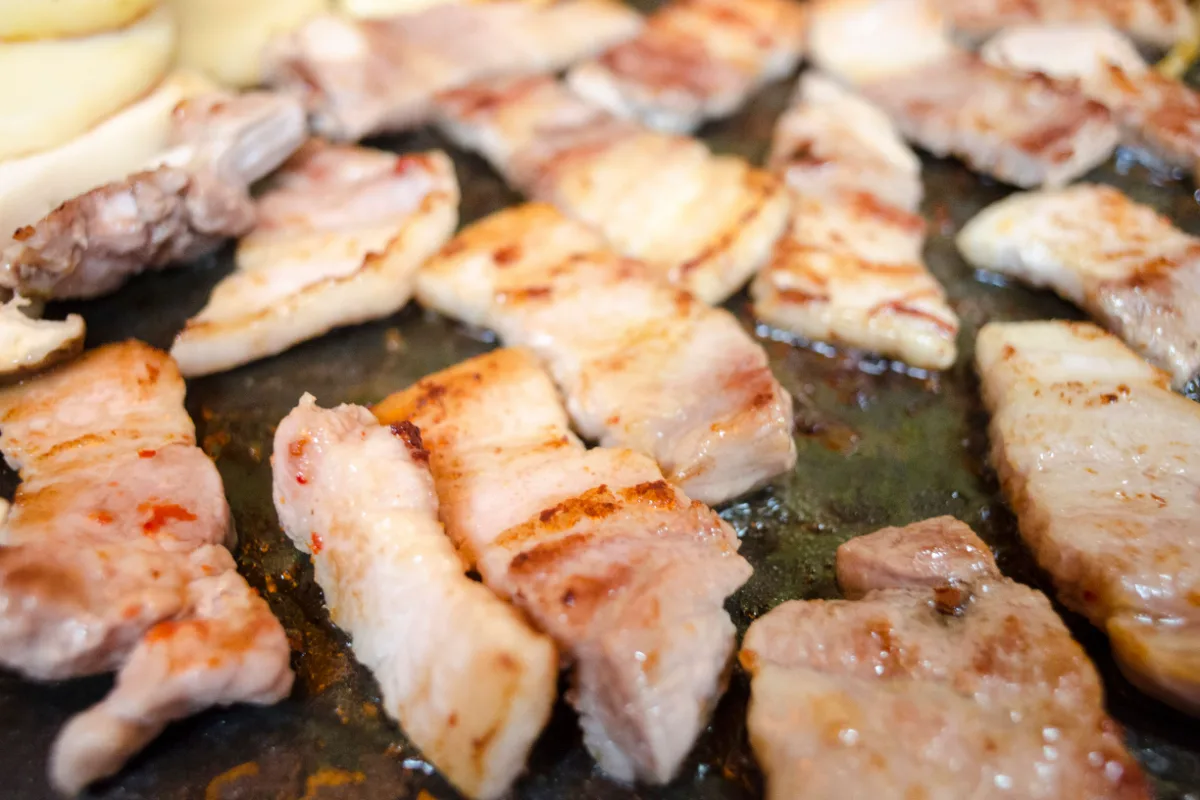 平らな鉄板で焼き色がついていく豚バラ