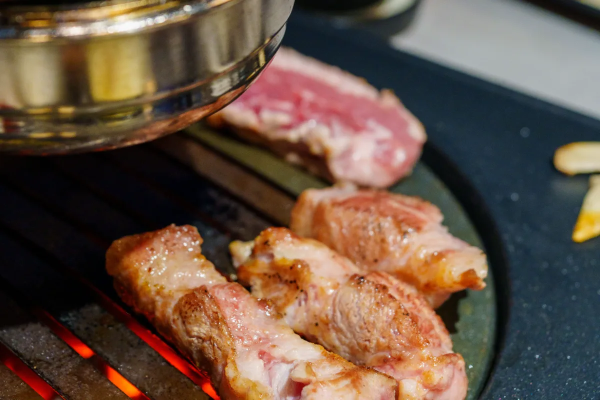 炭火が透けて見える丸い網の上の厚切り豚肉
